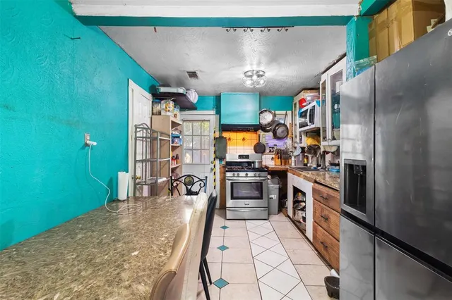 a kitchen with stainless steel appliances kitchen island granite countertop a refrigerator and a stove top oven