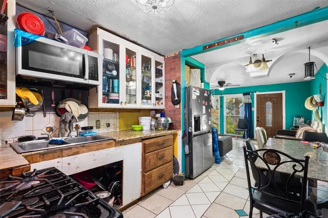 a kitchen filled with a stove a sink and a dining table with wooden floor