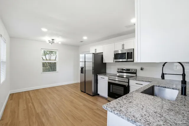 a kitchen with stainless steel appliances granite countertop a sink dishwasher stove top oven and refrigerator