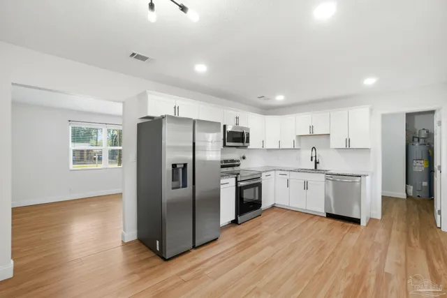 a kitchen with stainless steel appliances a refrigerator sink and wooden floor