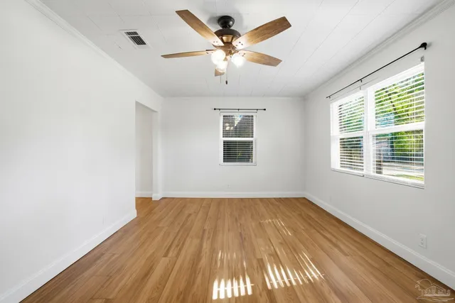 a view of an empty room with wooden floor and a window