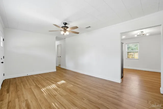 an empty room with wooden floor and a ceiling fan