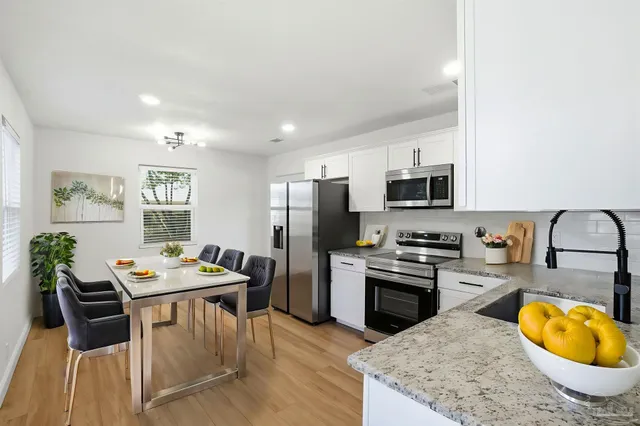 a kitchen with stainless steel appliances granite countertop a stove top oven a sink a dining table and chairs