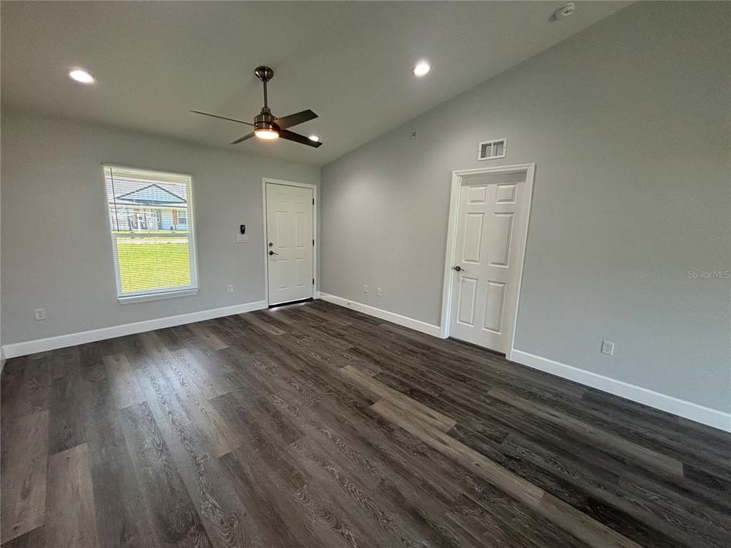 13187 Southwest 103rd Place Dunnellon, FL 34432 - Photo 15 of 24 an empty room with wooden floor chandelier fan and windows