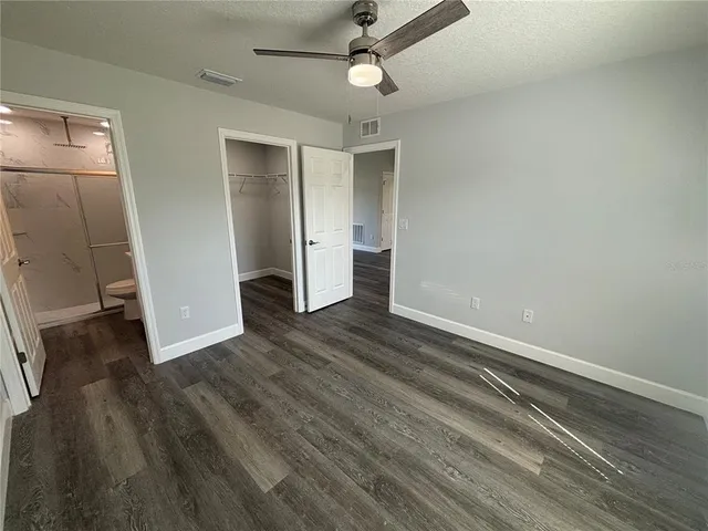 an empty room with wooden floor and ceiling fan