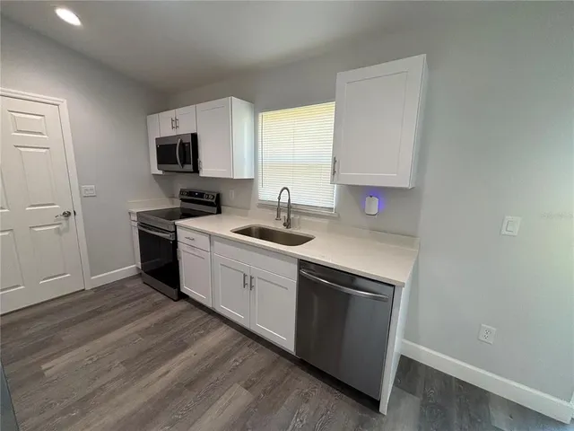 a kitchen with a sink cabinets and wooden floor