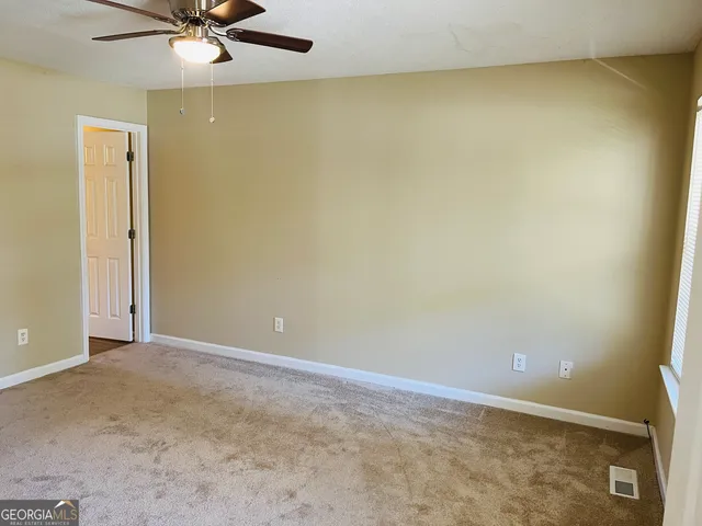 an empty room with a ceiling fan and carpet