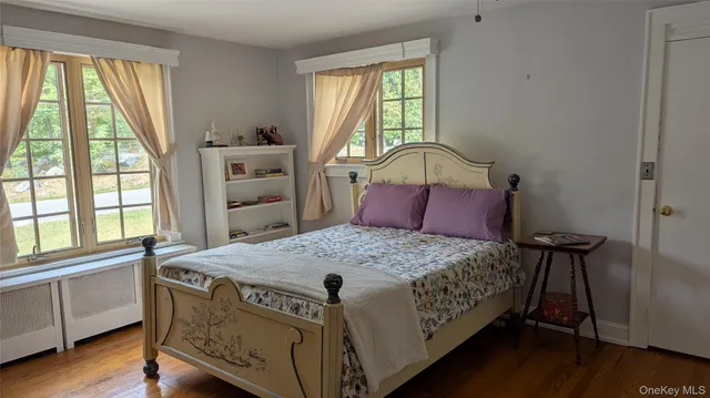 a bedroom with a bed a dresser next to a window