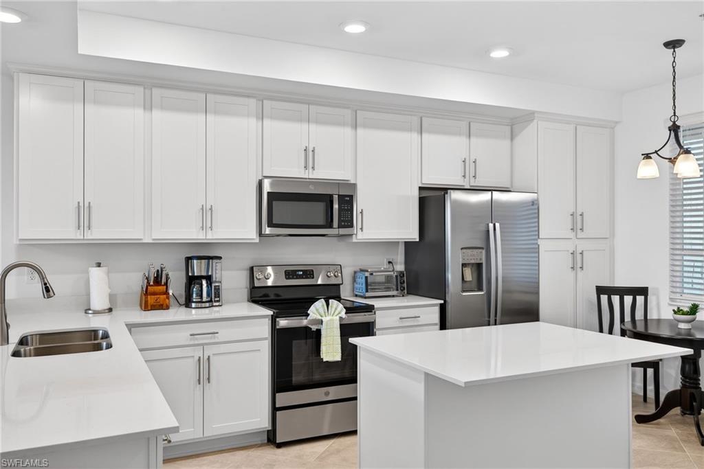 43985 Boardwalk Loop, Unit 2115 Punta Gorda, FL 33982 - Photo 3 of 28 a kitchen with white cabinets and stainless steel appliances