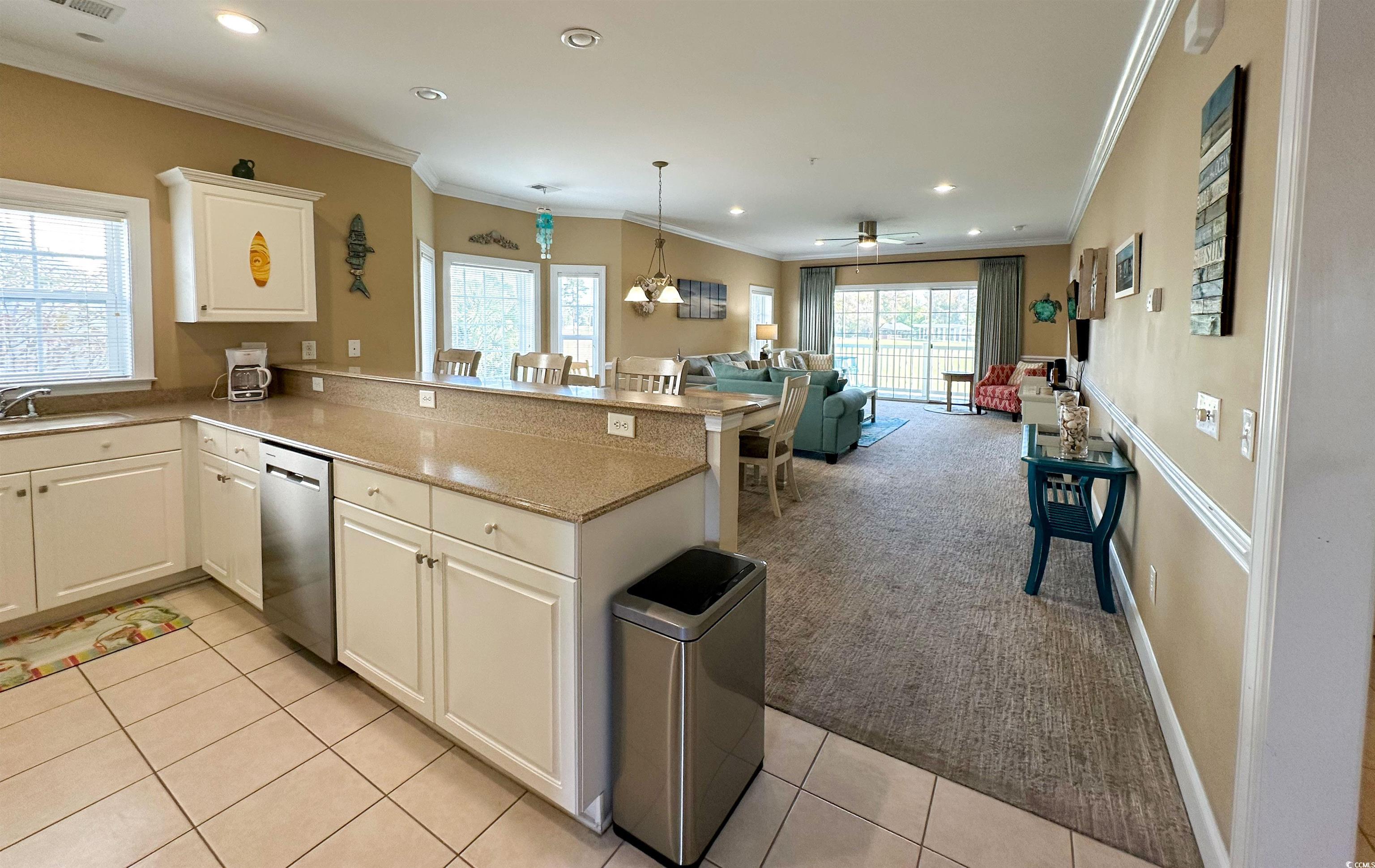 1004 Ray Costin Way, Unit 206 Murrells Inlet, SC 29576 - Photo 8 of 29 Kitchen featuring light colored carpet, dishwasher, kitchen peninsula, ornamental molding, and white cabinets