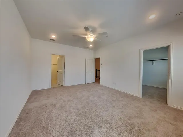 an empty room with closet and a ceiling fan