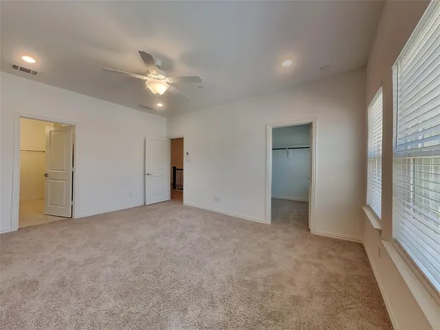 an empty room with closet and a ceiling fan