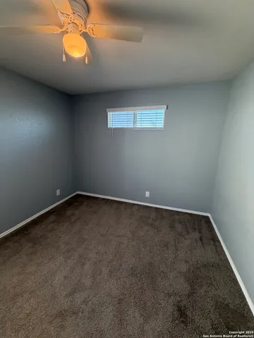 an empty room with a chandelier fan and window