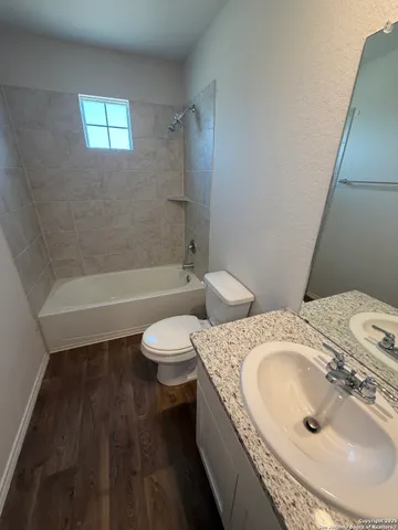 a bathroom with a granite countertop toilet sink and mirror