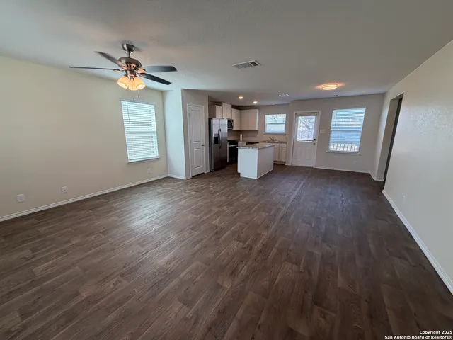 a view of an empty room with window and wooden floor