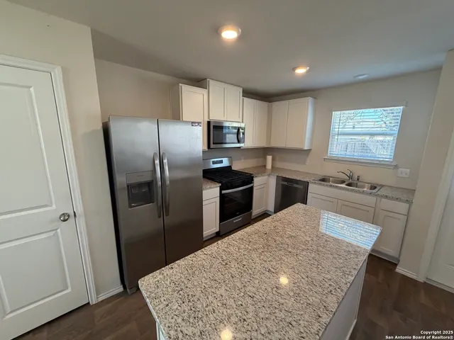 a kitchen with stainless steel appliances granite countertop a refrigerator sink and stove