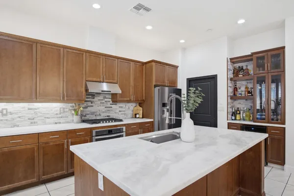 a kitchen with stainless steel appliances kitchen island granite countertop a refrigerator a sink and a stove