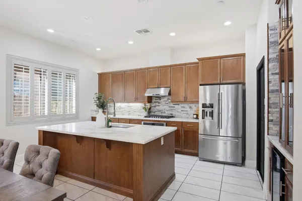 a kitchen with stainless steel appliances granite countertop a refrigerator a sink a stove a oven and a refrigerator with wooden floor