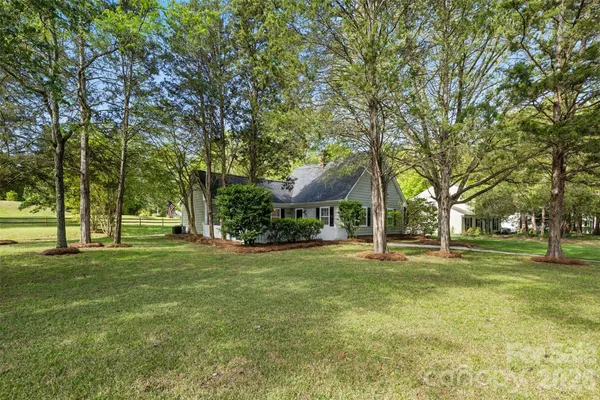 a view of a house with a big yard and large trees