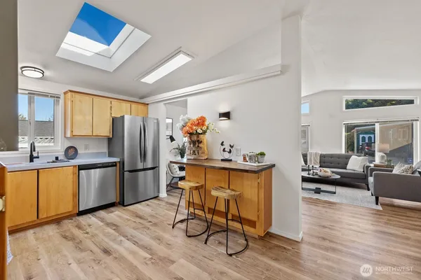 a kitchen with stainless steel appliances a refrigerator a stove a sink dishwasher a dining table and chairs with wooden floor