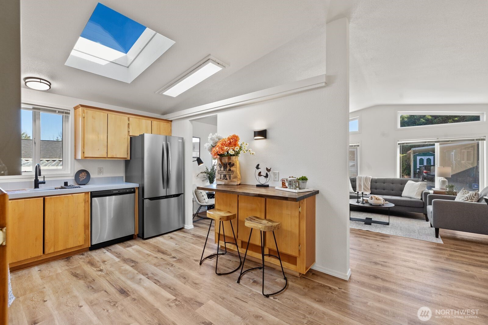 23825 15th Avenue Southeast, Unit 311 Bothell, WA 98021 - Photo 10 of 24 a kitchen with stainless steel appliances a refrigerator a stove a sink dishwasher a dining table and chairs with wooden floor