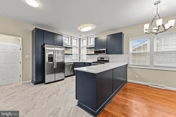 a kitchen with kitchen island a counter top space cabinets a stove and a refrigerator