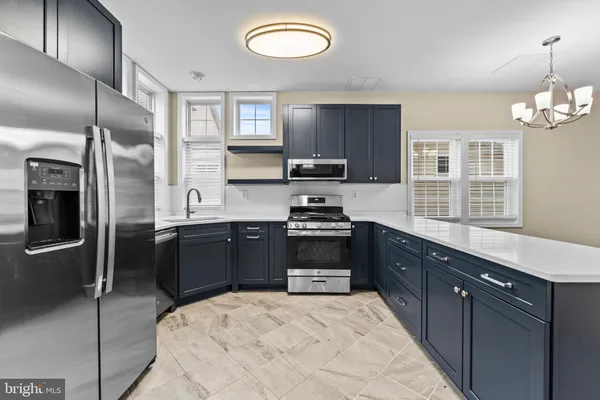 a kitchen with stainless steel appliances granite countertop a refrigerator a sink dishwasher a stove and a refrigerator