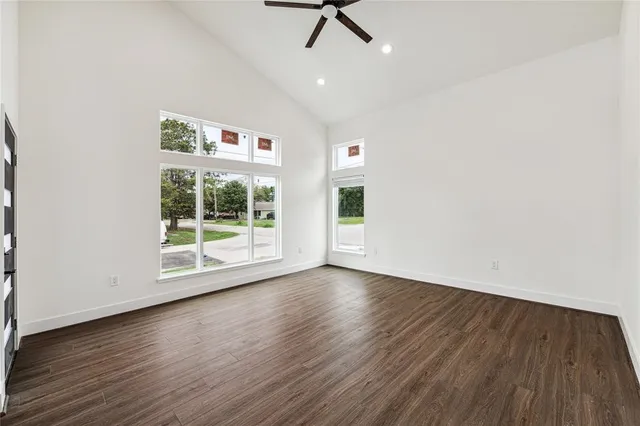 an empty room with wooden floor fan and windows
