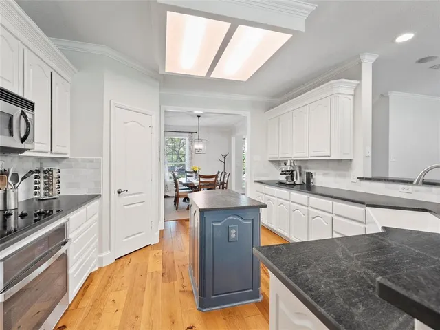 a large kitchen with stainless steel appliances granite countertop a lot of counter space and wooden floors