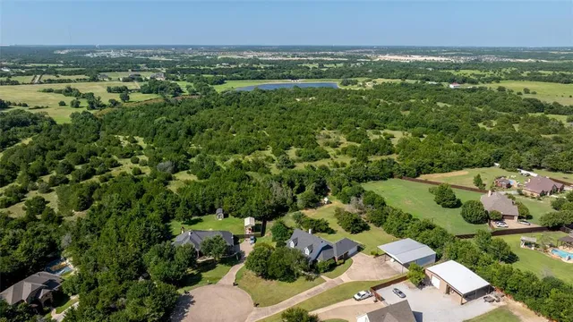 an aerial view of residential houses with outdoor space and trees