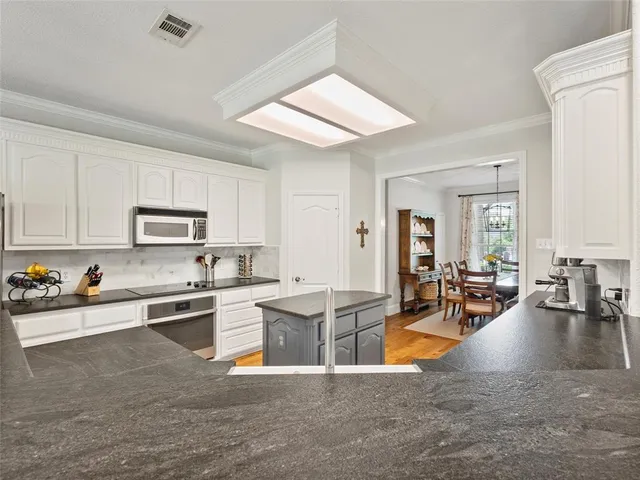 a view of a kitchen with kitchen island stainless steel appliances refrigerator stove microwave and cabinets