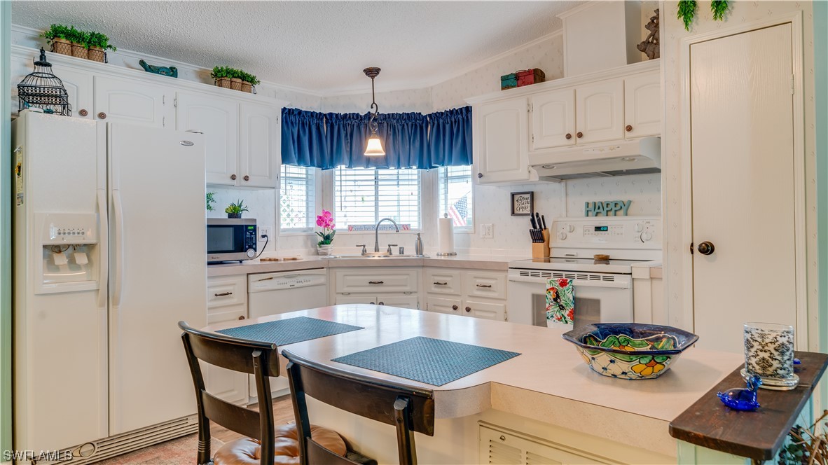 a kitchen with stainless steel appliances granite countertop a table chairs stove and white cabinets