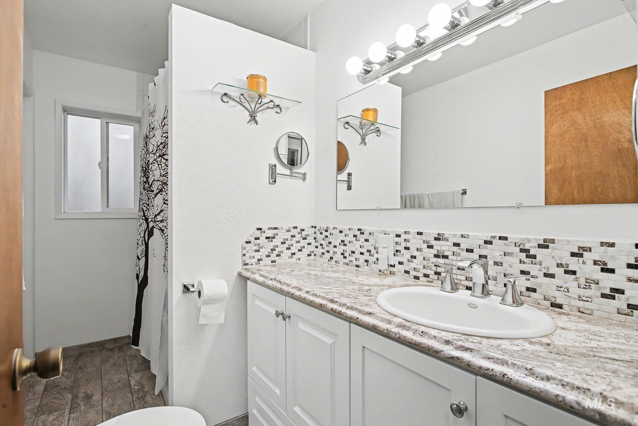 1103 3rd Street Asotin, WA 99402 - Photo 9 of 44 Full bath with vanity, backsplash, a shower with shower curtain, and dark wood-style flooring