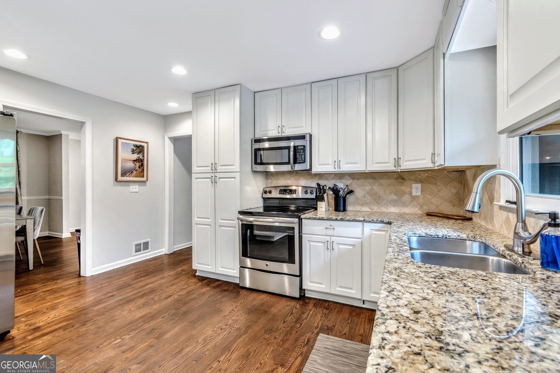 1897 Mt Vernon Road Dunwoody, GA 30338 - Photo 14 of 40 a kitchen with granite countertop wooden floors and stainless steel appliances