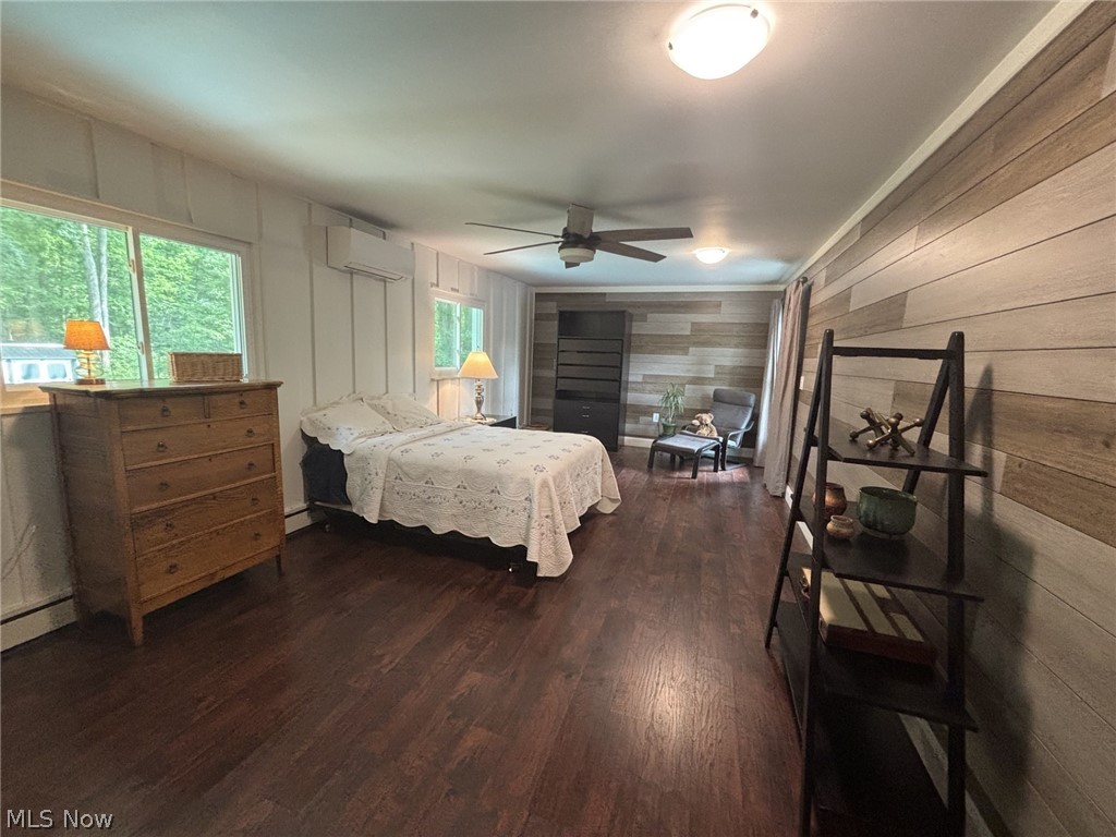 11385 County Line Road Chesterland, OH 44026 - Photo 12 of 26 Second spacious bedroom has engineered wood flooring, accent walls with horizontal wood paneling, white vertical paneling, ceiling fan with integrated lighting, and a wall-mounted mini-split system for zoned air conditioning.