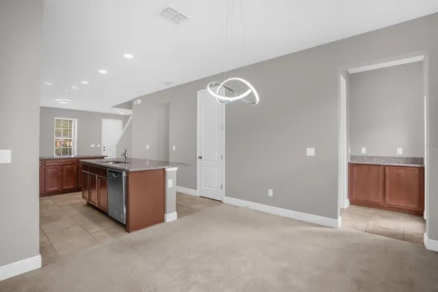 a view of kitchen with stainless steel appliances granite countertop cabinets and chandelier