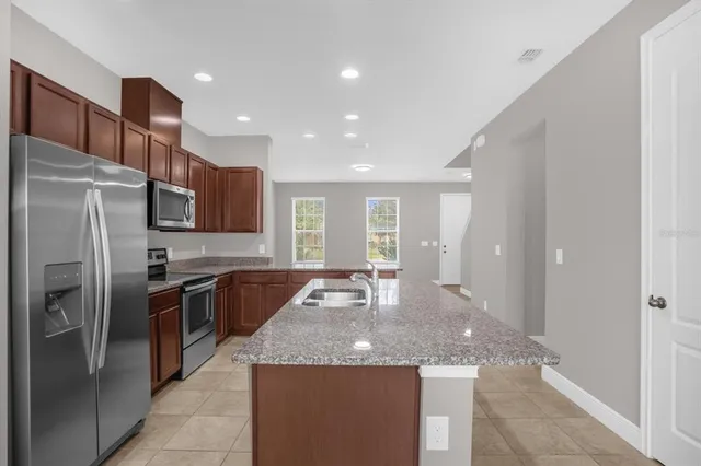 a kitchen with stainless steel appliances granite countertop wooden cabinets a granite counter tops and a refrigerator