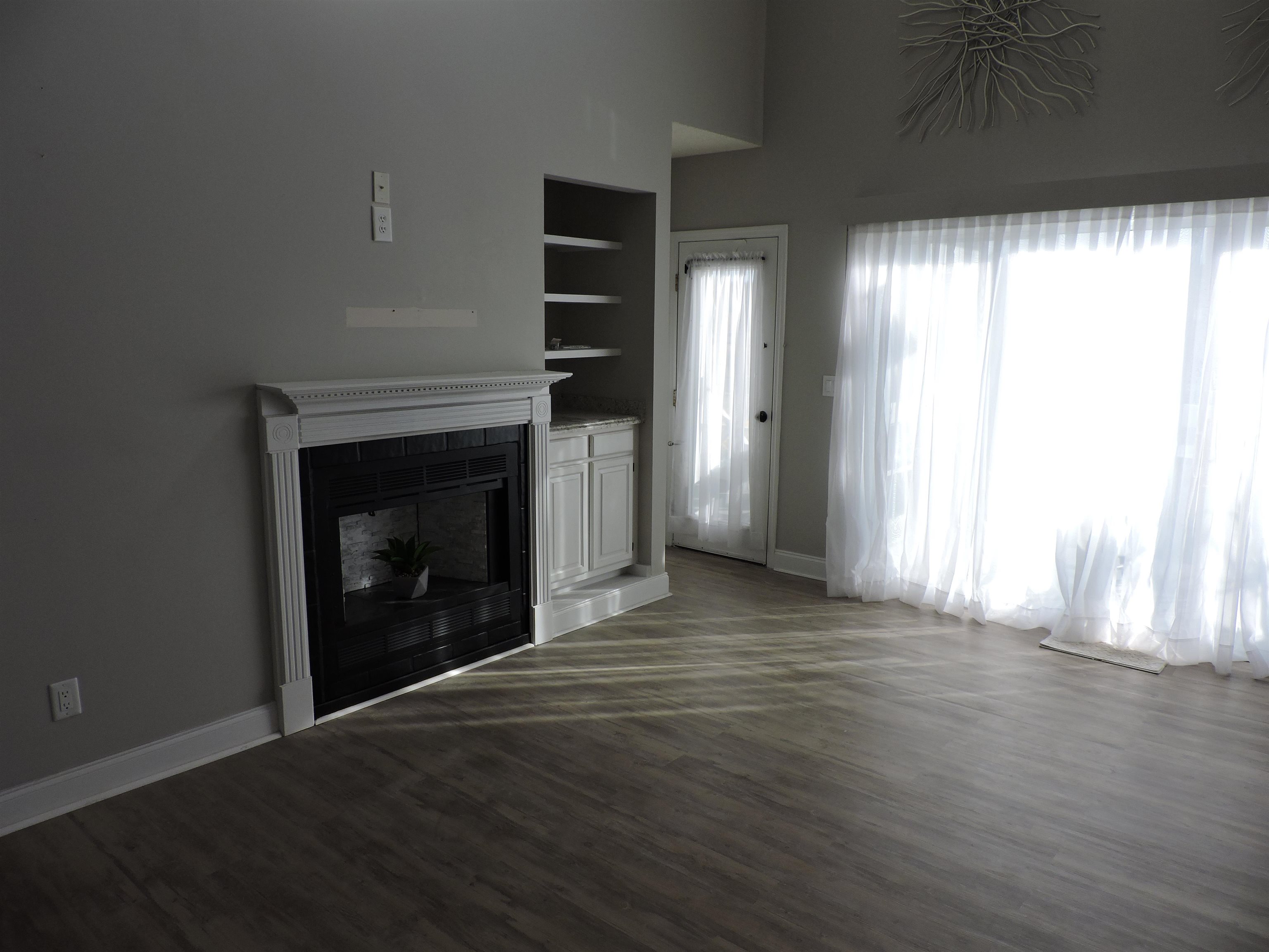 4396 Baldwin Avenue, Unit 80 Little River, SC 29566 - Photo 15 of 40 Unfurnished living room featuring a fireplace, dark wood-type flooring, built in shelves, and a towering ceiling