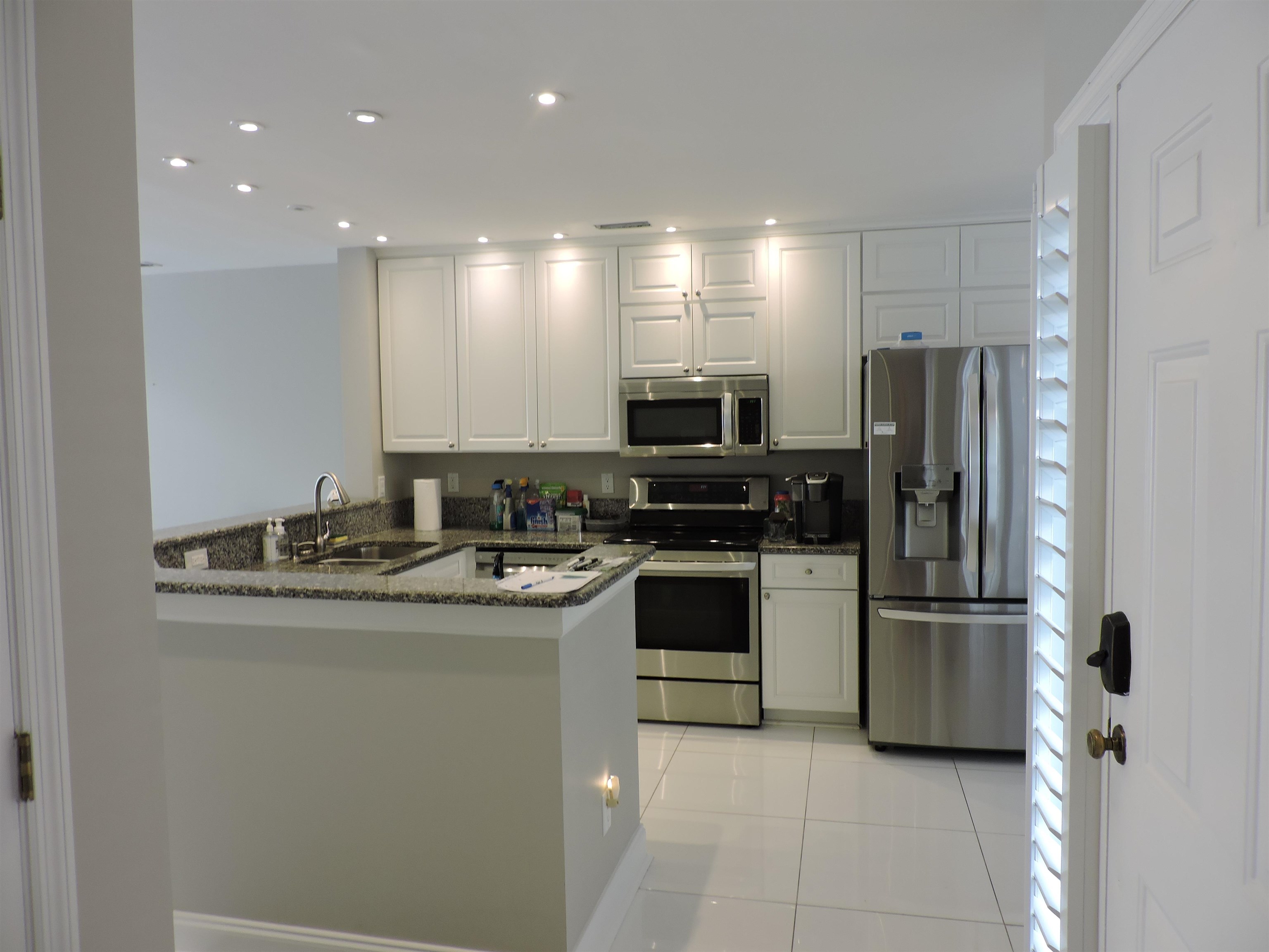4396 Baldwin Avenue, Unit 80 Little River, SC 29566 - Photo 9 of 40 Kitchen featuring dark stone countertops, appliances with stainless steel finishes, a peninsula, white cabinets, and light tile patterned floors