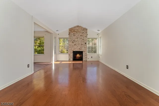 a view of a livingroom with wooden floor a fireplace and windows