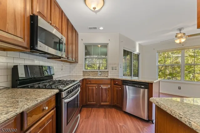 a kitchen with stainless steel appliances granite countertop a stove a sink and a microwave