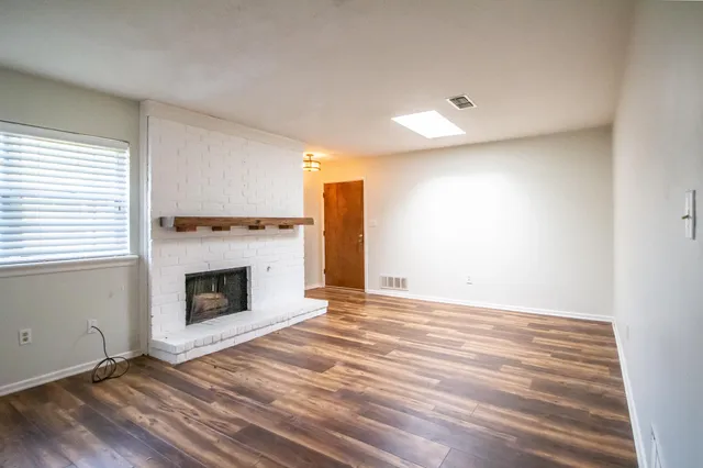 a view of empty room with wooden floor and fireplace