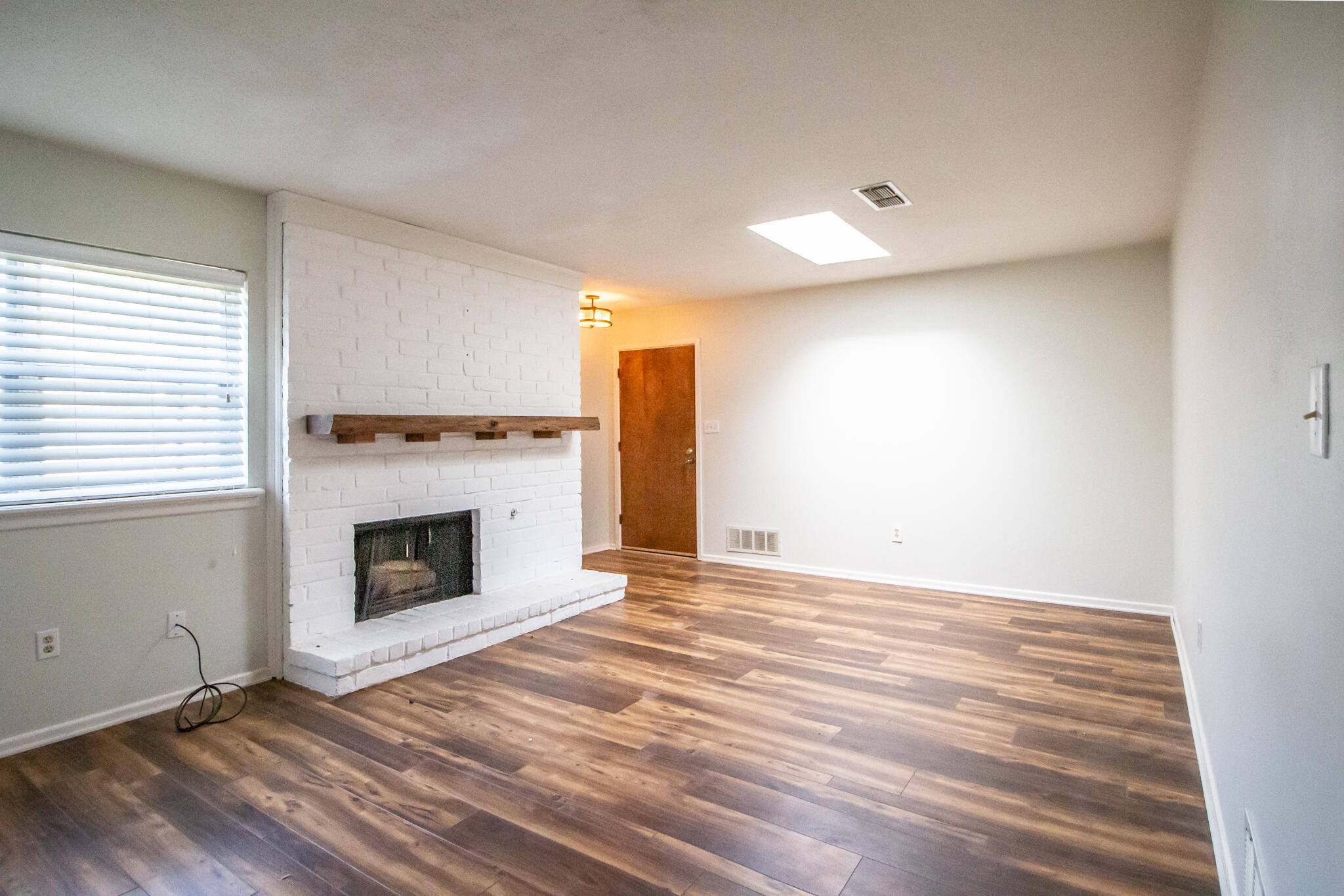 a view of empty room with wooden floor and fireplace