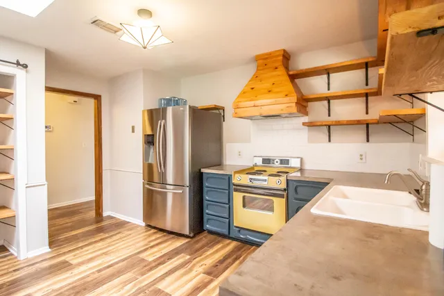 a kitchen with stainless steel appliances granite countertop a refrigerator and a stove top oven