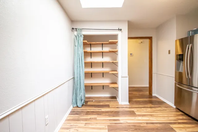 a view of a hallway with wooden cabinet and a refrigerator