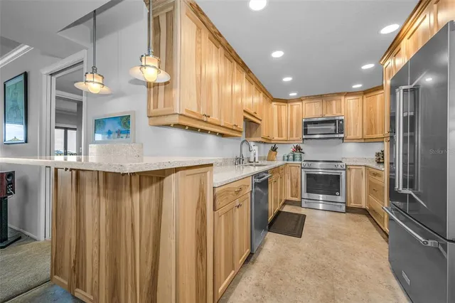a kitchen with granite countertop stainless steel appliances a refrigerator stove top oven and sink