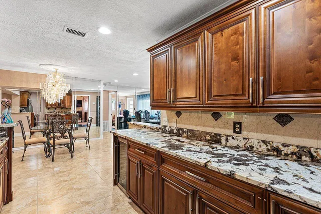 a kitchen with stainless steel appliances granite countertop a stove top oven a sink a dining table and chairs with wooden floor