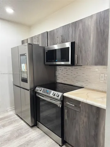 a kitchen with granite countertop cabinets stainless steel appliances and wooden floor