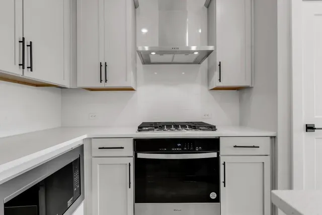 a kitchen with stainless steel appliances granite countertop a stove a white cabinet and a granite counter tops