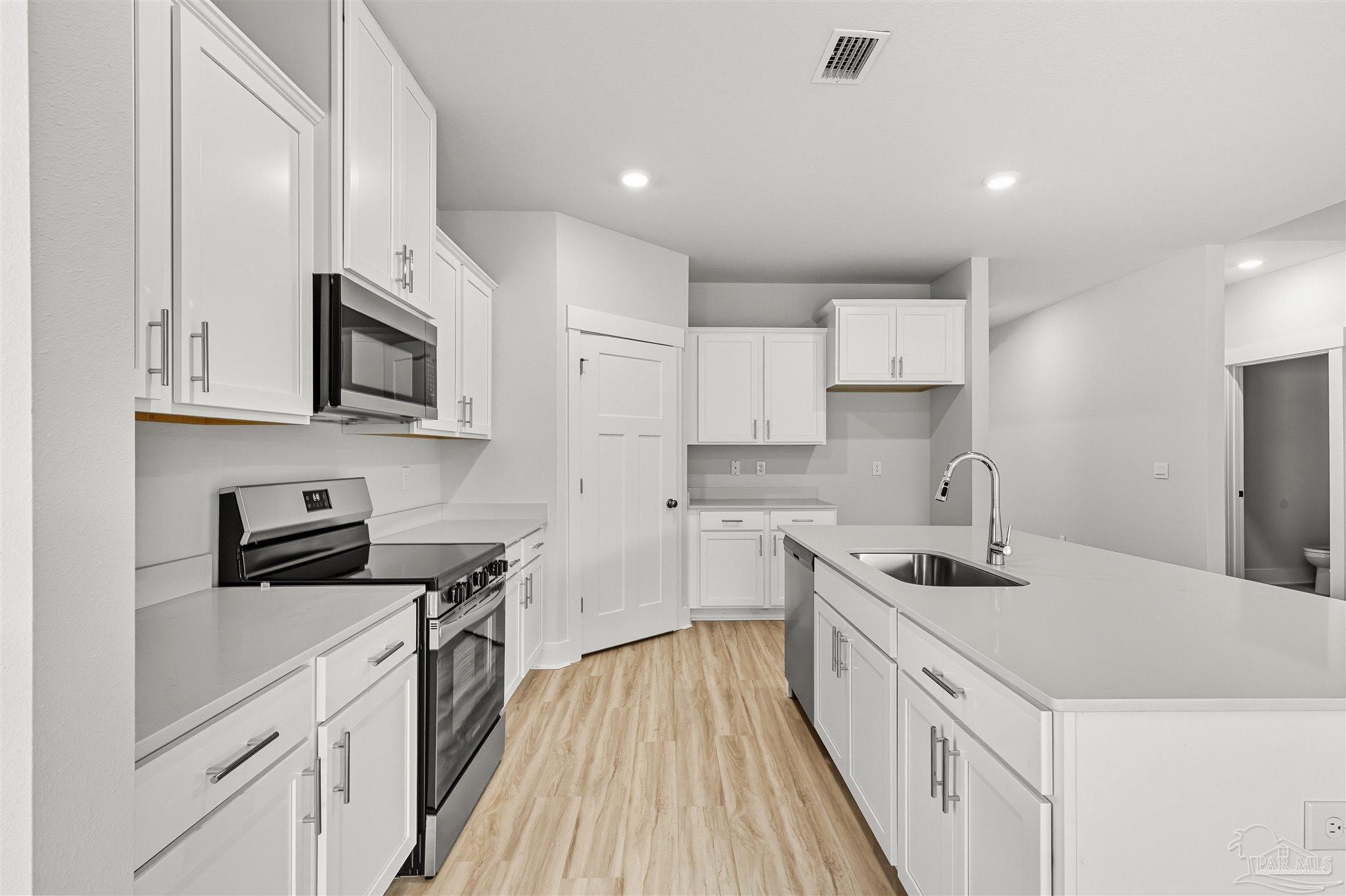 4733 Redhead Court Pace, FL 32571 - Photo 19 of 48 a kitchen with stainless steel appliances a sink dishwasher a stove top oven a refrigerator with white cabinets and wooden floor